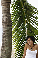 Young woman sitting under palm tree and smiling - Alex Mares-Manton