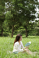 woman sitting on grass reading a book - Alex Mares-Manton