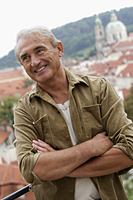 mature man folding his arms and smiling with city as background - Alex Hajdu
