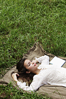 young woman lying on grass outside with eyes closed - Alex Mares-Manton