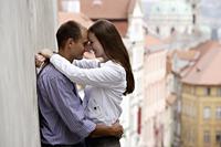 young couple hugging next to wall with old buildings in background - Alex Hajdu