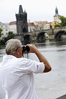 back view of mature man looking through binoculars - Alex Hajdu