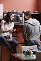 young couple cooking in kitchen smiling at each other - Alex Mares-Manton