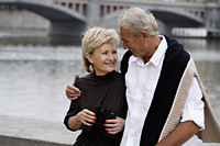 mature couple sitting near bridge looking at each other and smiling - Alex Hajdu