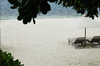 wooden lounge chairs with umbrella on beach - Alex Mares-Manton