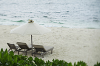 wooden lounge chairs under umbrella on beach - Alex Mares-Manton