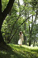 young woman wearing white dress walking among trees - Alex Mares-Manton