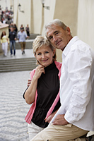 mature couple standing on street smiling - Alex Hajdu