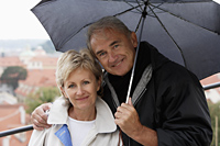 mature couple standing under an umbrella and smiling - Alex Hajdu