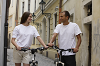 young couple walking with bikes through street - Alex Hajdu