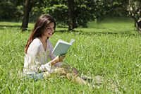 woman sitting on grass reading a book - Alex Mares-Manton