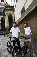 young couple with bicycles holding map and looking up - Alex Hajdu