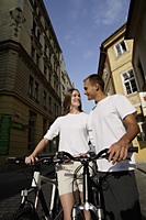 young couple holding bikes looking at each other - Alex Hajdu