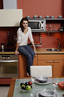 young woman sitting on kitchen counter - Alex Mares-Manton