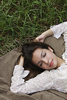 head shot of young woman lying on grass with eyes closed - Alex Mares-Manton