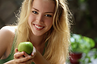 head shot of young woman holding green apple - Alex Mares-Manton