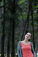 young woman looking up at trees smiling - Alex Mares-Manton