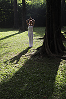 Young woman doing yoga under trees - Alex Mares-Manton