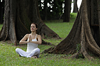young woman sitting and doing yoga under trees - Alex Mares-Manton