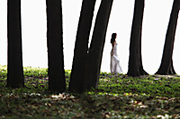 woman wearing white dress standing amongst trees - Alex Mares-Manton
