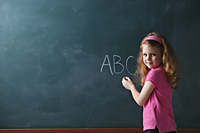 Young girl writing abc on chalk board - Nugene Chiang