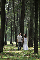 woman and man holding hands and walking amongst trees - Alex Mares-Manton