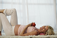 pregnant woman laying on floor holding apple - Alex Mares-Manton