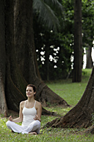 young woman sitting under trees doing yoga - Alex Mares-Manton