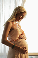 blond pregnant woman looking at her belly and smiling - Alex Mares-Manton