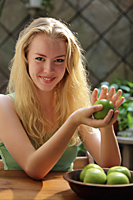 Young woman holding a green apple and smiling - Alex Mares-Manton